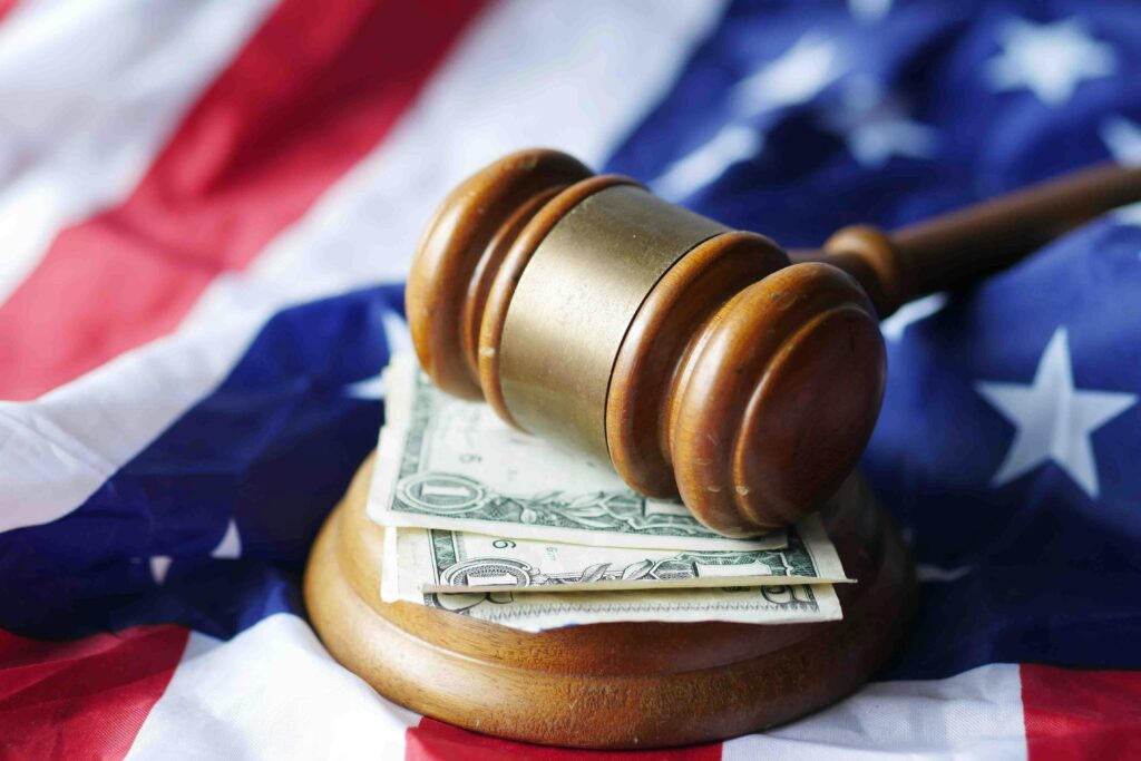 A gavel resting on dollar bills atop the American flag, symbolizing justice and finance.