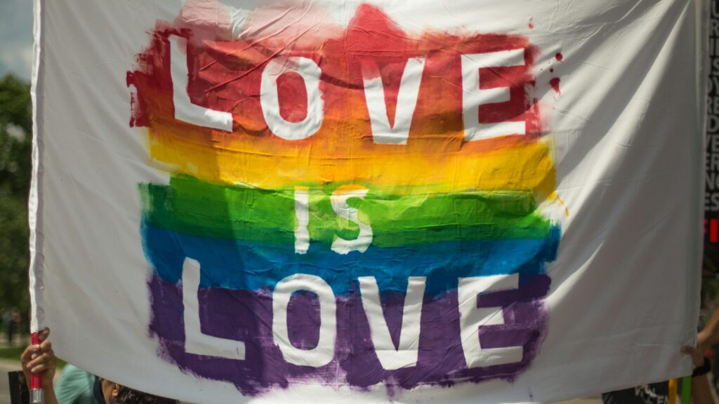 LGBTQI+ RIGHTS; GENDER-BASED VIOLENCE, DISCRIMINATION & EQUAL PAY Colorful 'Love is Love' pride banner at a parade in London, Ontario celebrating equality and diversity.