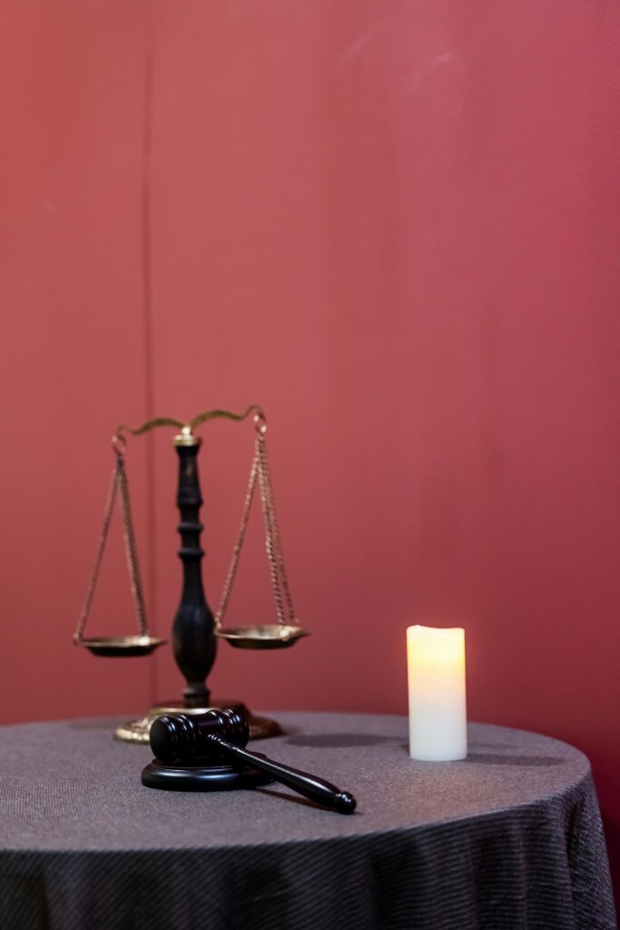 A symbolic display of justice featuring a gavel, scales, and candle on a table.