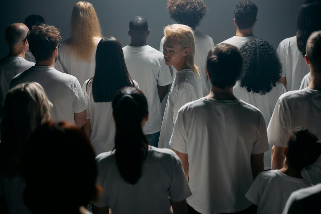 A diverse crowd stands together in a studio, exploring themes of individuality and social connections.