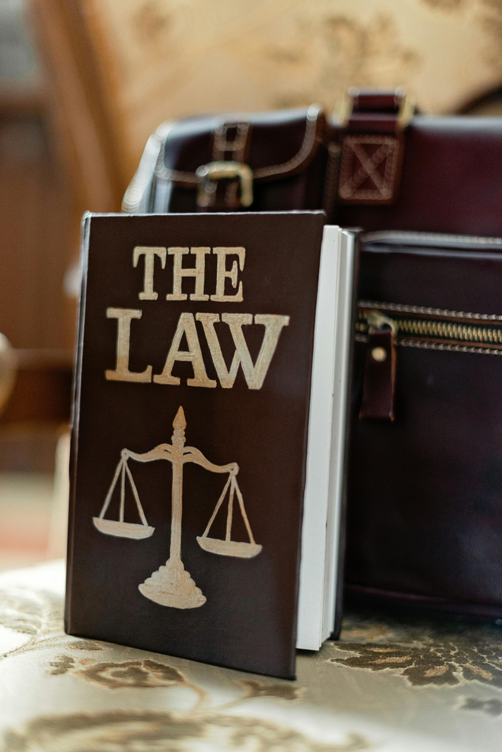 Close-up of a law book titled 'The Law' beside a leather briefcase.